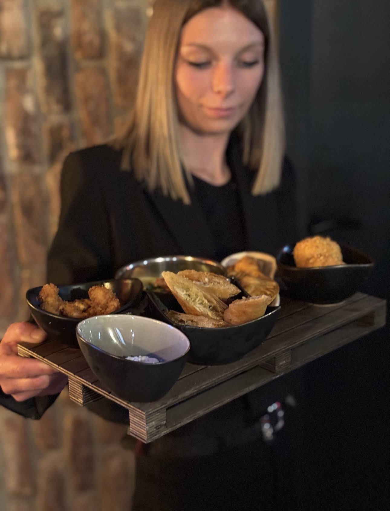 Carelle, en salle au Tribe Roture, présentant un plateau d'apéro