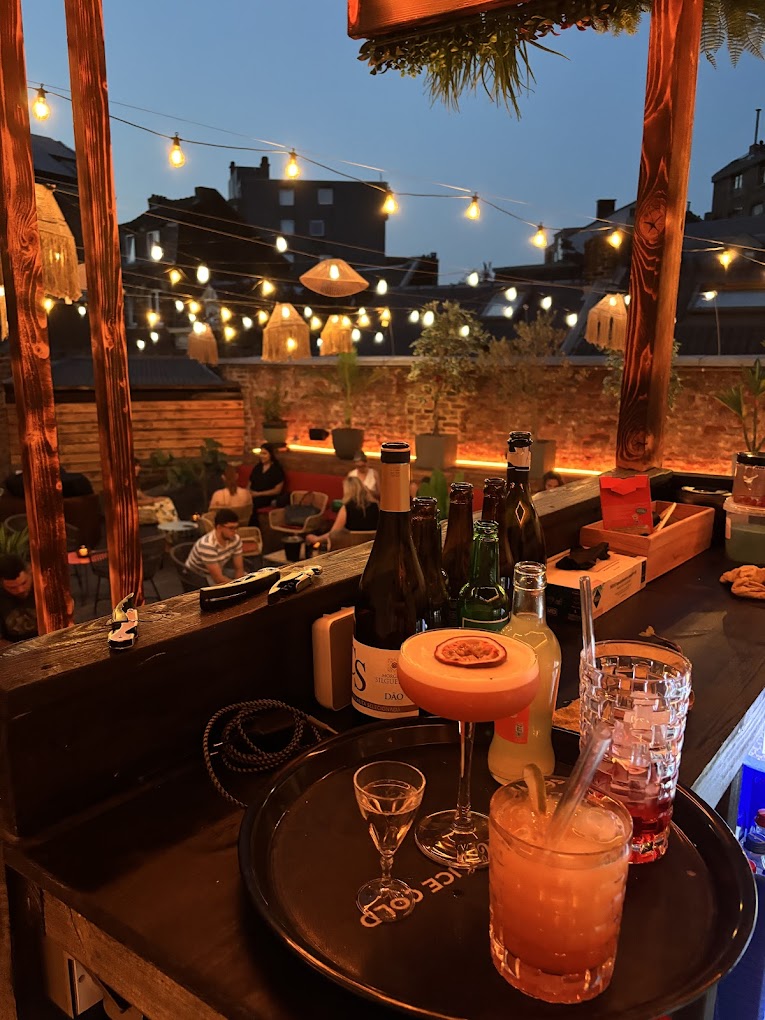 Le rooftop du Tribe au crépuscule, guirlandes lumineuses et cocktails sur le bar
